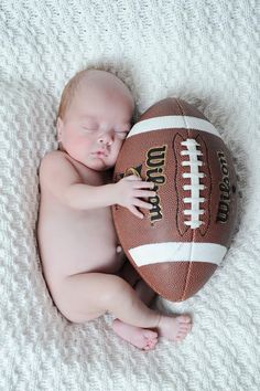 a baby is sleeping next to a football