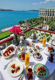 the table is set with plates of food and drinks on it, overlooking the ocean