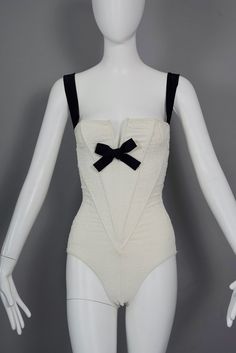 Features: - 100% Authentic CHRISTIAN LACROIX. - Ivory white wired corset bodysuit/ swimsuit with embossed brocade pattern. - Contrasting black strap and bow accent. - Tag reads: CHRISTIAN LACROIX PARIS Made in France, Size 38.  - Fabric Composition: 88% Nylon 12% Elastan - The black straps are a bit loose. - Excellent vintage condition. Will fit Small to Medium. Measurements taken laid flat, please double bust, waist and hips: Bust: 13.38 inches (34 cm) without stretching Waist: 10.63 inches (27 White Underwire Party Corset, White Underwire Corset For Parties, Elegant White Sleeveless Bodysuit, Chic White Underbust Corset, White Underwire Boned Bodice Corset, White Underwire Corset With Boned Bodice, Summer White Underwire Corset, White Summer Evening Bodysuit, White Evening Bodysuit For Summer