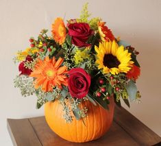 a pumpkin filled with flowers on top of a wooden table