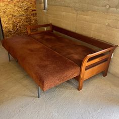 a wooden bed frame sitting in the middle of a room next to a brick wall