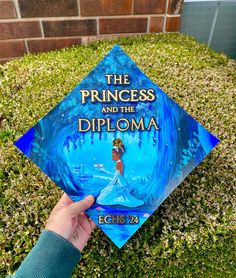 someone is holding up a blue graduation cap with the princess and the frog on it