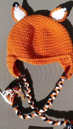 an orange knitted hat with white and black fox ears on top of it's brim