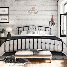 a bedroom with white brick walls and black iron bed frame, pillows, rugs and pictures on the wall