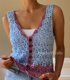 a woman wearing a blue and pink crocheted vest with buttons on the front