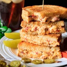 a stack of grilled sandwiches sitting on top of a white plate next to pickles