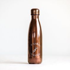 a copper colored water bottle sitting on top of a white table