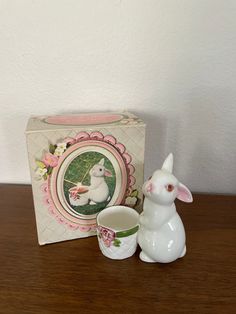 a white bunny figurine sitting next to a coffee cup and box on a table