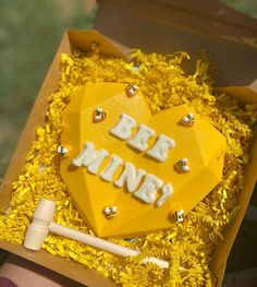 a yellow heart shaped cake with the words be mine on it in a cardboard box