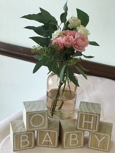 a vase filled with flowers sitting next to blocks that spell out the word oh baby