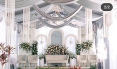 a room with white drapes and flowers on the ceiling is decorated with greenery