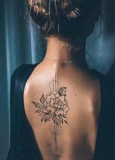 the back of a woman's neck with a flower tattoo on her left side