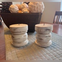 two white candles sitting on top of a wooden table