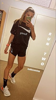 a woman is taking a selfie in the mirror wearing running shorts and nike t - shirt