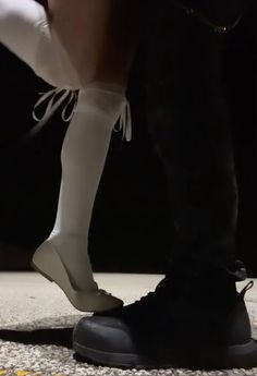 the legs and feet of a person in white socks, black boots and knee high socks