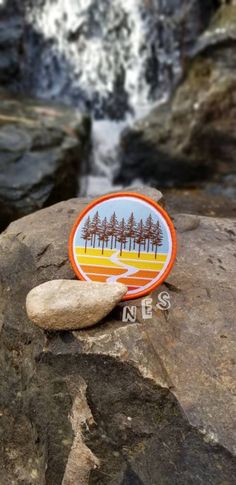 a pin sitting on top of a rock next to a river