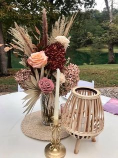 an arrangement of flowers in a vase on top of a table with a candle holder