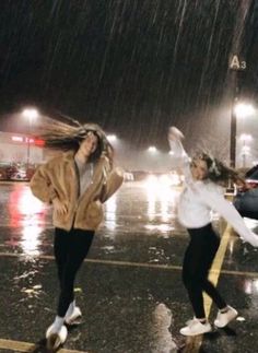 two girls jumping in the air on a rainy night with their hair blowing in the wind