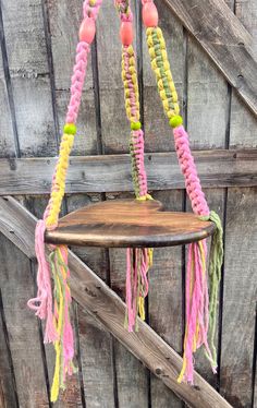 a wooden table topped with pink, yellow and green macrame tassels