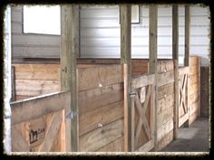 the inside of a horse barn with wooden stalls