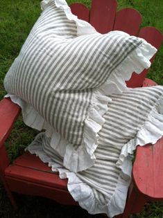 a red bench with a striped pillow on top of it and some grass in the background