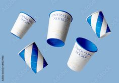 four blue and white paper cups flying in the air