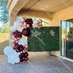 balloon arch in front of a building with white and pink balloons