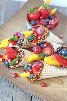 an image of some fruit cones on top of a wooden table with chocolate and strawberries