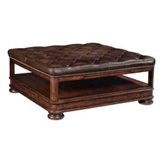 a brown leather ottoman sitting on top of a wooden table