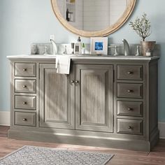 a bathroom with blue walls and wooden flooring, a large round mirror above the sink