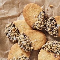 several cookies with chocolate toppings on top of brown paper and some nuts in the middle