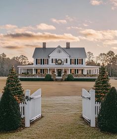 a large white house with two trees in front of it