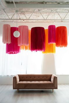 a living room filled with furniture and lots of colorful decorations hanging from the ceiling next to a window