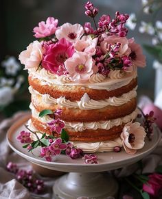 a multi layer cake with pink and white flowers on the top is sitting on a plate