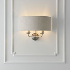 a light fixture mounted on the wall with a lamp shade over it's head