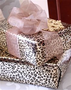 two gift boxes with bows and leopard print wrapping paper on them, one has a pink bow