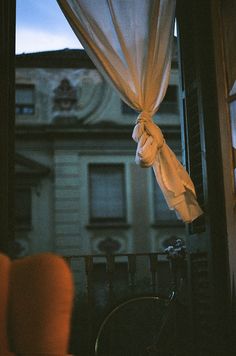 a bicycle is parked in front of a window with curtains hanging from it's sides