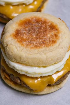 two hamburgers with cheese and an egg on top are sitting next to each other