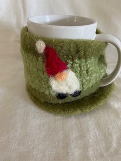 a green cup with a santa clause on it and a white mug in the middle