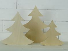 three wooden christmas trees on a shelf against a white brick wall, one is cut out and the other is made from plywood