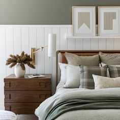 a bed with pillows and blankets in a bedroom next to two pictures on the wall