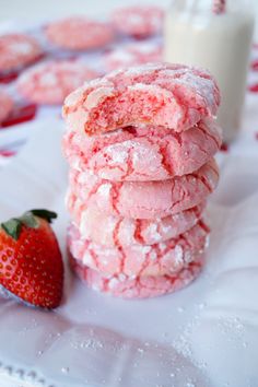 a stack of pink cookies next to a strawberry