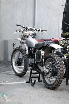 a dirt bike is parked next to a plant in a parking lot near a building