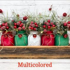 four mason jars filled with red and green christmas decorations sitting on top of a wooden shelf