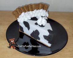 a piece of cake with white frosting and black cow print on it sitting on a plate