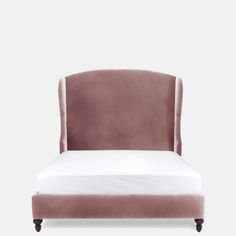 an upholstered bed with white sheets and pink velvet