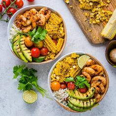 two bowls filled with shrimp, corn, and avocado on top of a cutting board