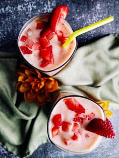 two cups with strawberries and ice cream in them on a green napkin next to a pine cone