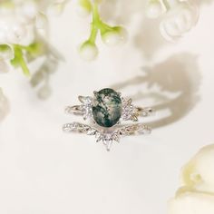 a ring with a green stone surrounded by white flowers