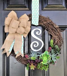 a wreath that has the letter s on it with succulents and plants